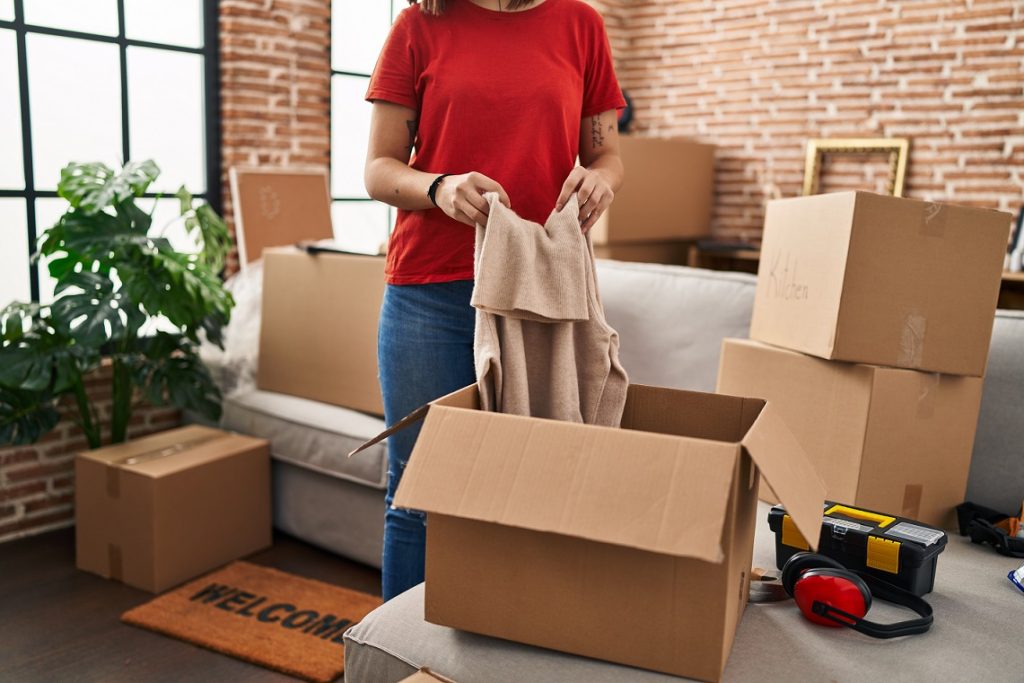 young beautiful hispanic woman unpacking cardboard box new home